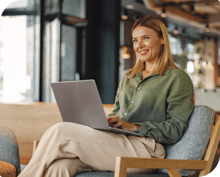 Woman smiling while working on a laptop in a modern office setting